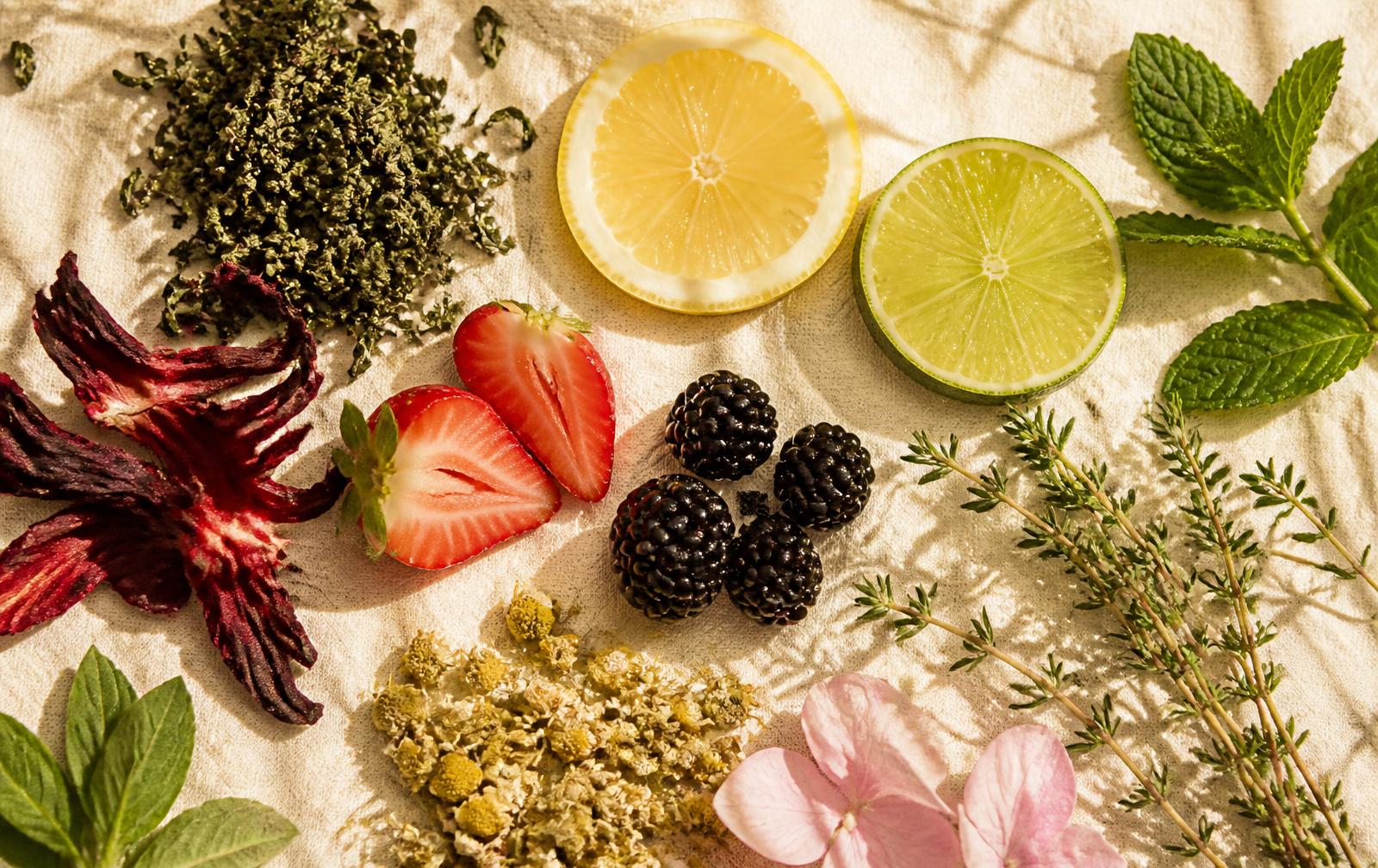Tea leaves, hibiscus, berries, citrus, mint and chamomile on ivory linen